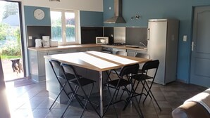 Una cocina con una isla central, microondas, estufa y refrigerador.