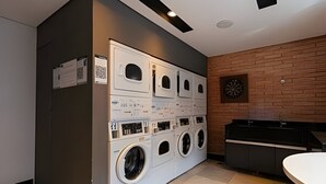 A laundry room with multiple washing machines and dryers, a sink, and a dartboard on the wall. - Requintado Studio Paulista Frei Caneca (São Paulo)