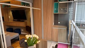 A modern interior with a dining area, a TV, and a kitchen with cabinets and a window. - Requintado Studio Paulista Frei Caneca (São Paulo)