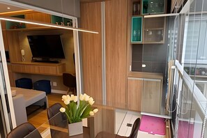 Ein modernes Interieur mit Essbereich, Fernseher und einer Küche mit Schränken und Fenster.