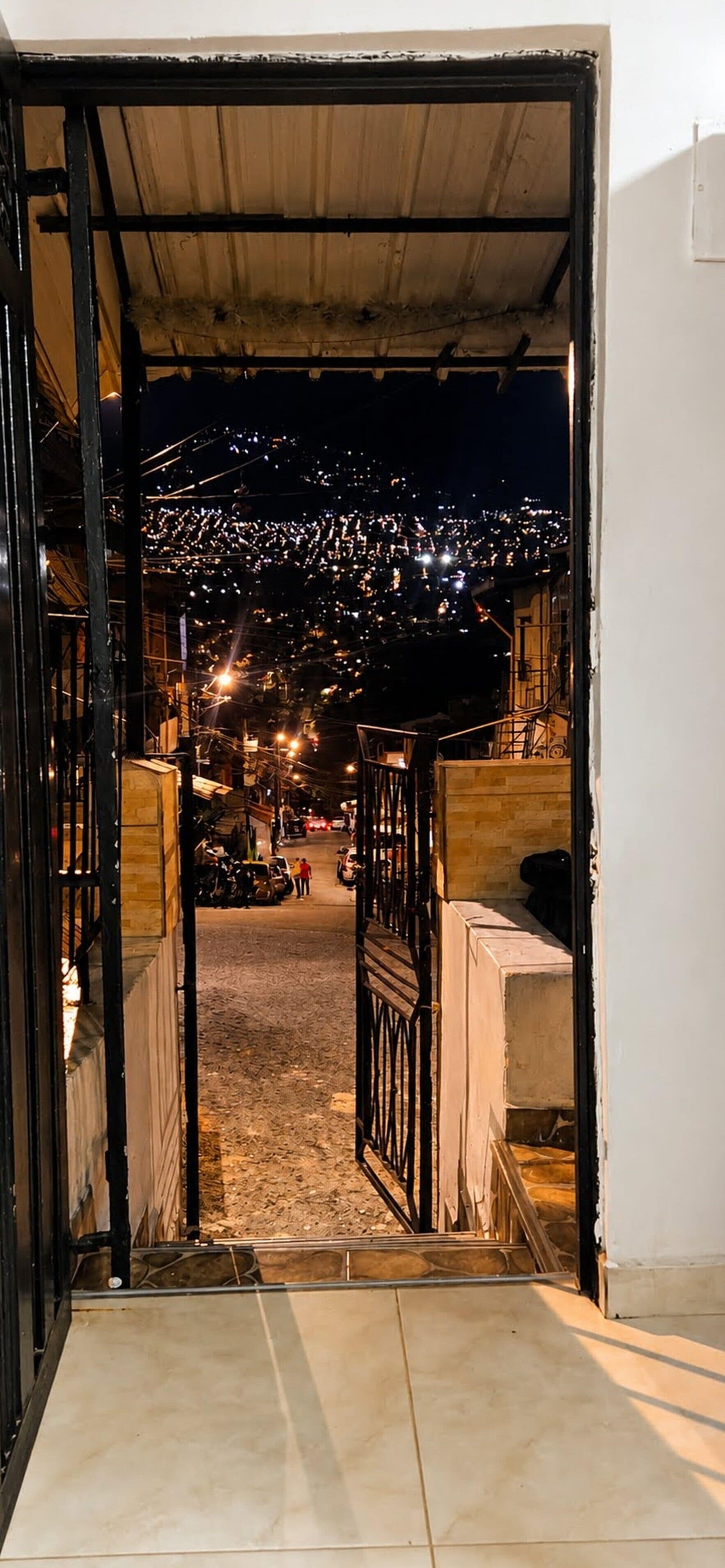 Een open deur die uitkomt op een straat met uitzicht op een stadsbeeld in de nacht.