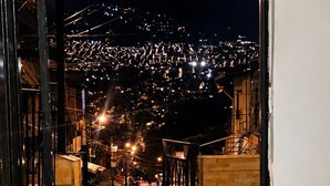 A porta aberta dá para uma rua com vista para o horizonte urbano noturno.