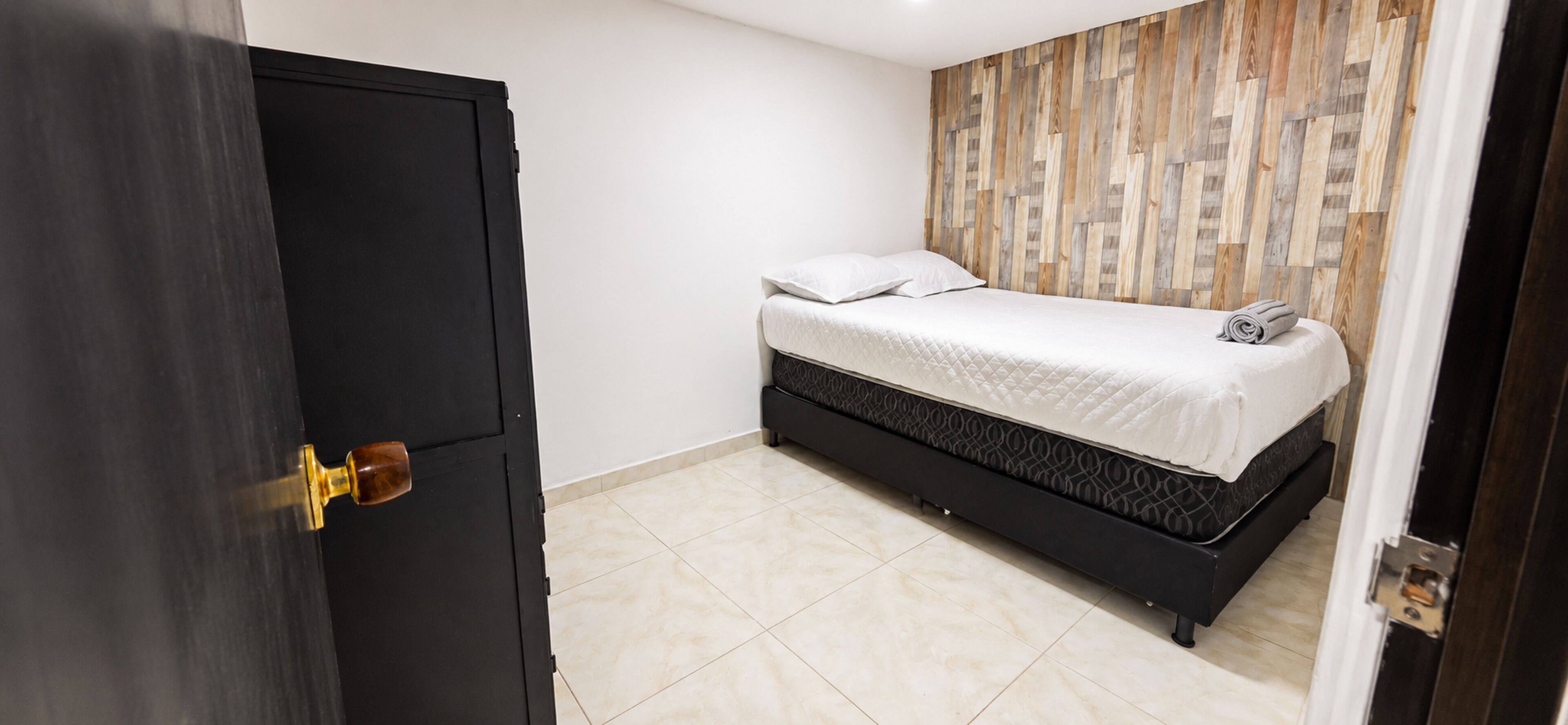 Une chambre à coucher avec un lit, une armoire et un panneau mural en bois.