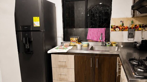 Uma cozinha equipada com geladeira, pia, armários e fogão.