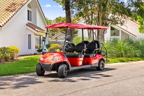 A red golf cart parked on a residential street. - Luxury Remodel and New Golf Cart (Miramar Beach)