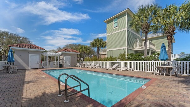 A swimming pool with a white fence, lounge chairs, and umbrellas. - Ahoy Matey - Emerald Waters (Miramar Beach)