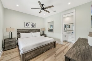 A bedroom with a bed, two bedside tables, a ceiling fan, and artwork on the walls. - Ahoy Matey - Emerald Waters (Miramar Beach)