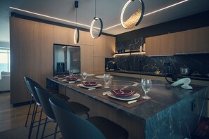 Eine moderne Küche mit Marmorarbeitsplatte, Holzschränken und Pendelleuchten.