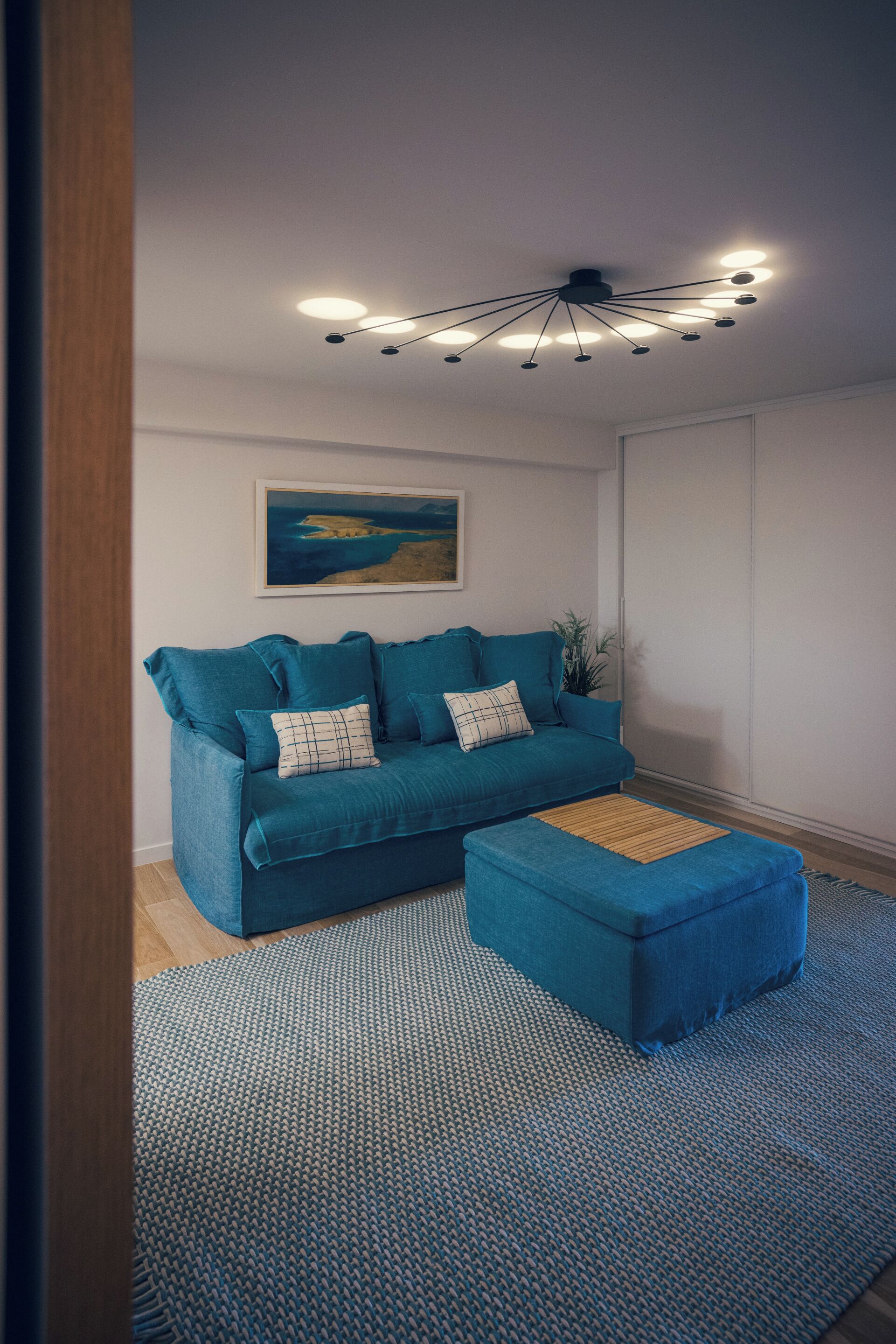 Ein modernes Wohnzimmer mit einem blauen Sofa, passendem Ottomanen und einem gemusterten Teppich.