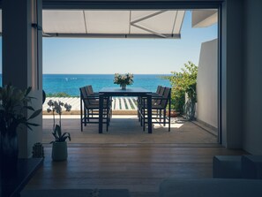 Un patio abierto con una mesa y sillas, una planta en maceta y vista al mar.