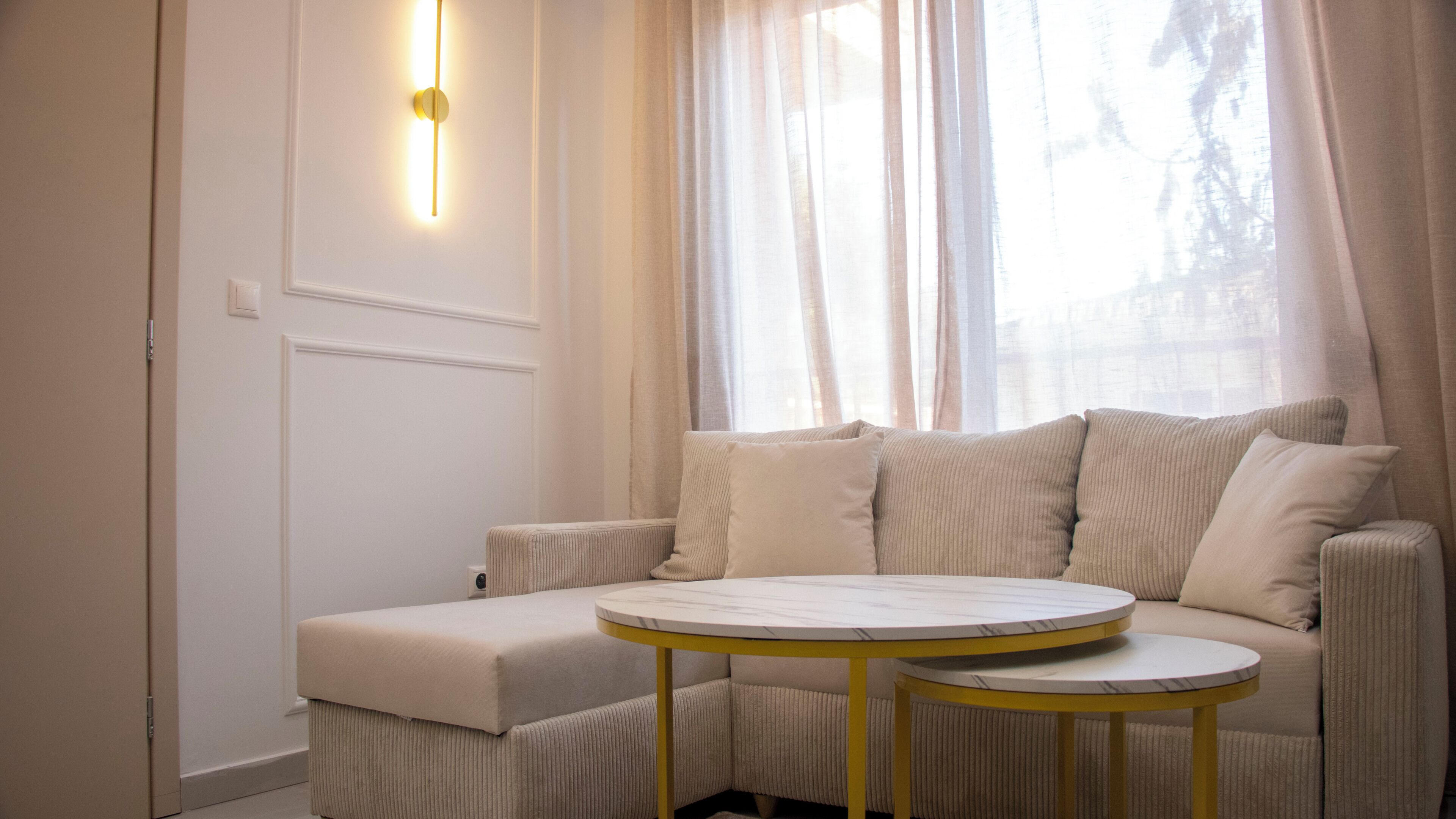 Un salon moderne avec un canapé, une petite table ronde et un luminaire fixé au mur.