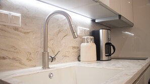 Una cocina con un lavamanos moderno, una cafetera y una campana extractora de acero inoxidable.