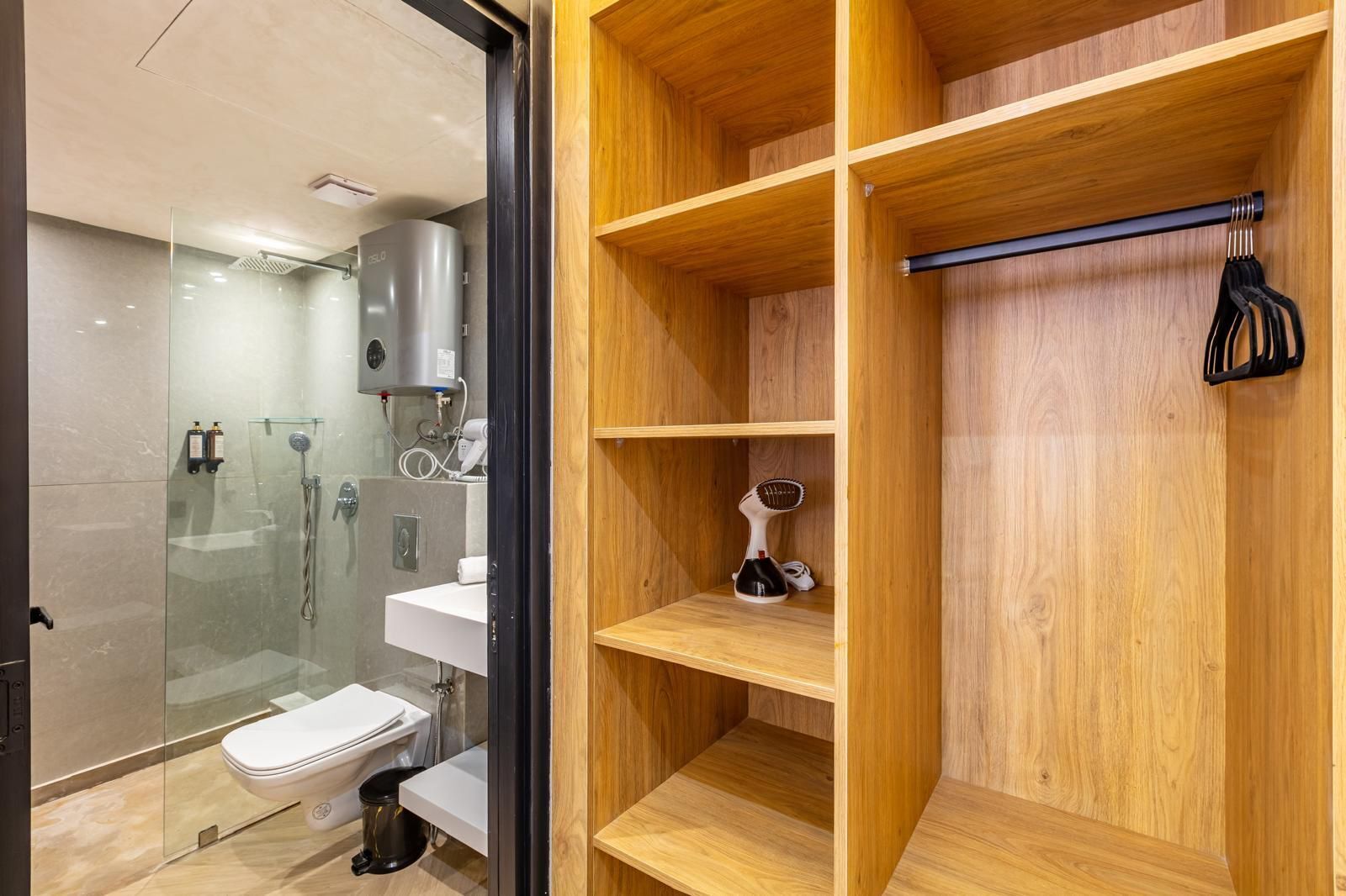 A modern bathroom with a glass-enclosed shower, a toilet, and a wooden vanity with a hairdryer.