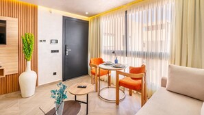 A modern living room with a sofa, a dining table with chairs, a TV mounted on a wooden panel, and a door with a handle. - LUXURY APARTH GUELIZ MARRAKECH AYLAL  (Safi)