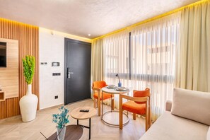 Un salon moderne comprenant un canapé, une table à manger avec des chaises, un téléviseur fixé sur un panneau en bois et une porte avec une poignée.