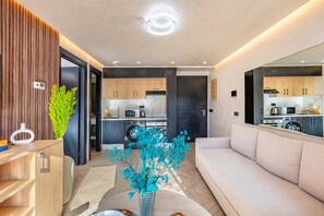 A modern kitchen with built-in appliances, a dining area with a sofa, and a living room with a large mirror.
