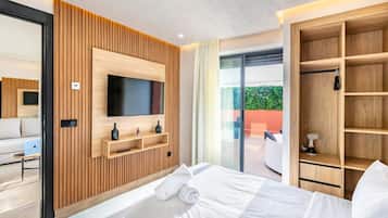Une chambre d’hôtel moderne équipée d’un lit, d’un téléviseur fixé sur un mur recouvert de panneaux en bois, d’une porte vitrée donnant sur un balcon et d’une armoire en bois.