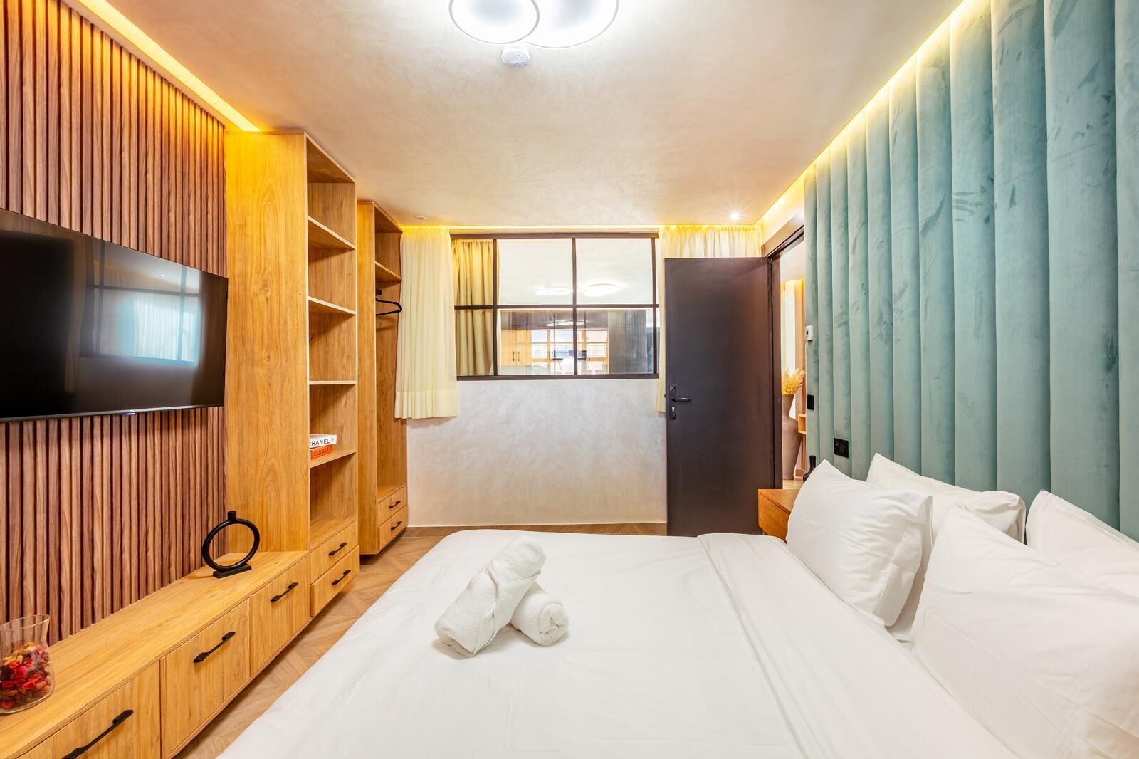 A hotel room with a bed, a TV, a wardrobe, and a window.