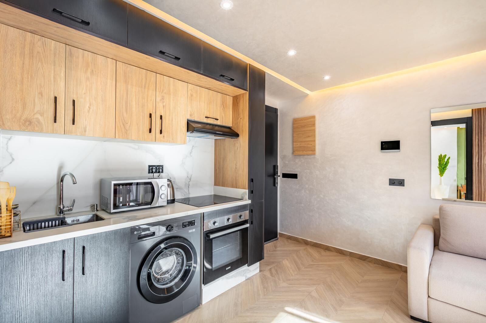A modern kitchen with built-in appliances, a washing machine, and a dining area with a sofa.