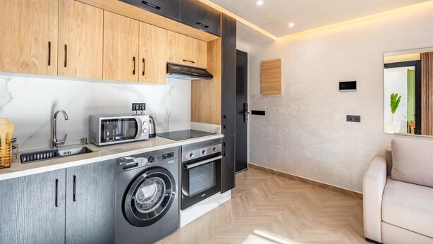A modern kitchen with built-in appliances, a washing machine, and a dining area with a sofa. - LUXURY APARTH GUELIZ MARRAKECH AYLAL  (Safi)