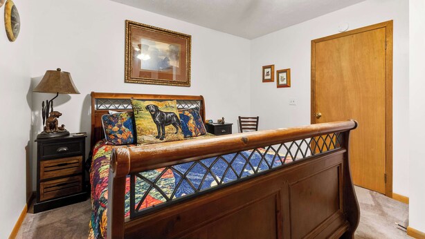 A bedroom with a wooden bed, a nightstand, a lamp, a ceiling fan, and a door. - Mountain Mist Cottage , Valley Views , Sleeps 6 (Sevierville)