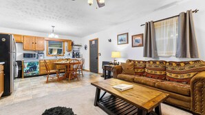 A compact living space with a kitchenette, dining area, and a sofa with patterned cushions. - Mountain Mist Cottage , Valley Views , Sleeps 6 (Sevierville)