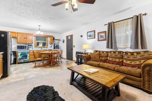A compact living space with a kitchenette, dining area, and a sofa with patterned cushions. - Mountain Mist Cottage , Valley Views , Sleeps 6 (Sevierville)