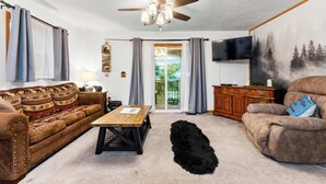 A living room with a ceiling fan, a sofa, a coffee table, a TV, and a painting on the wall. - Mountain Mist Cottage , Valley Views , Sleeps 6 (Sevierville)