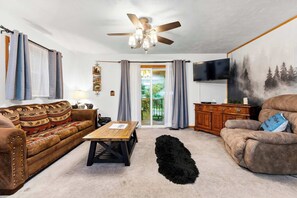 A living room with a ceiling fan, a sofa, a coffee table, a TV, and a painting on the wall. - Mountain Mist Cottage , Valley Views , Sleeps 6 (Sevierville)