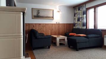 A living room with two sofas, a coffee table, a painting on the wall, and a window with blinds.