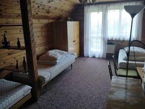 A cozy cabin-style room with two single beds, a wooden wardrobe, a table, and a lamp. - Cottage IRENA in Giant Mountains (Čistá v Krkonoších)