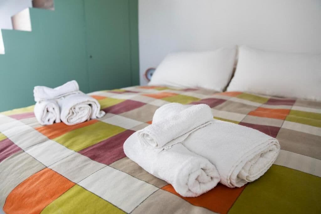 Una cama con un edredón colorido y toallas blancas dobladas con cuidado.