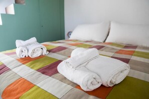 A bed with a colorful quilt and neatly folded white towels. - CasaMaGà  (Naples)