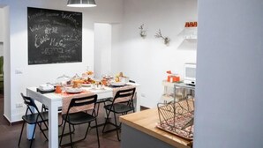 A dining area with a white table set for four, a chalkboard with various words, and a small kitchen area with a microwave and a basket. - CasaMaGà  (Naples)