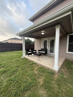 A covered patio with outdoor furniture, a concrete floor, and a view of a neighboring house. - Hill Country Retreat Minutes to Gruene, Rivers & Canyon Lake (New Braunfels)