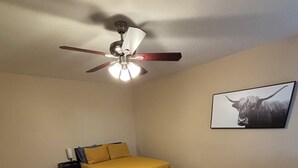 Ein Schlafzimmer mit einem Bett, einem Deckenventilator, einem Teppich und einem an der Wand hängenden Bild.