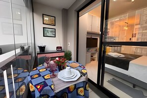 Ein modernes Zimmer mit Esstisch für zwei Personen, einer Couch und einem großen Fenster.