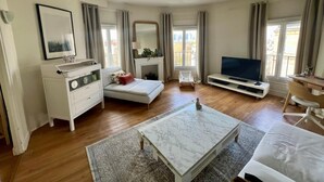 Een moderne woonkamer met een bank, een televisie, een open haard en een groot raam.
