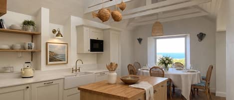 A spacious kitchen with a central island, wooden flooring, and a skylight.