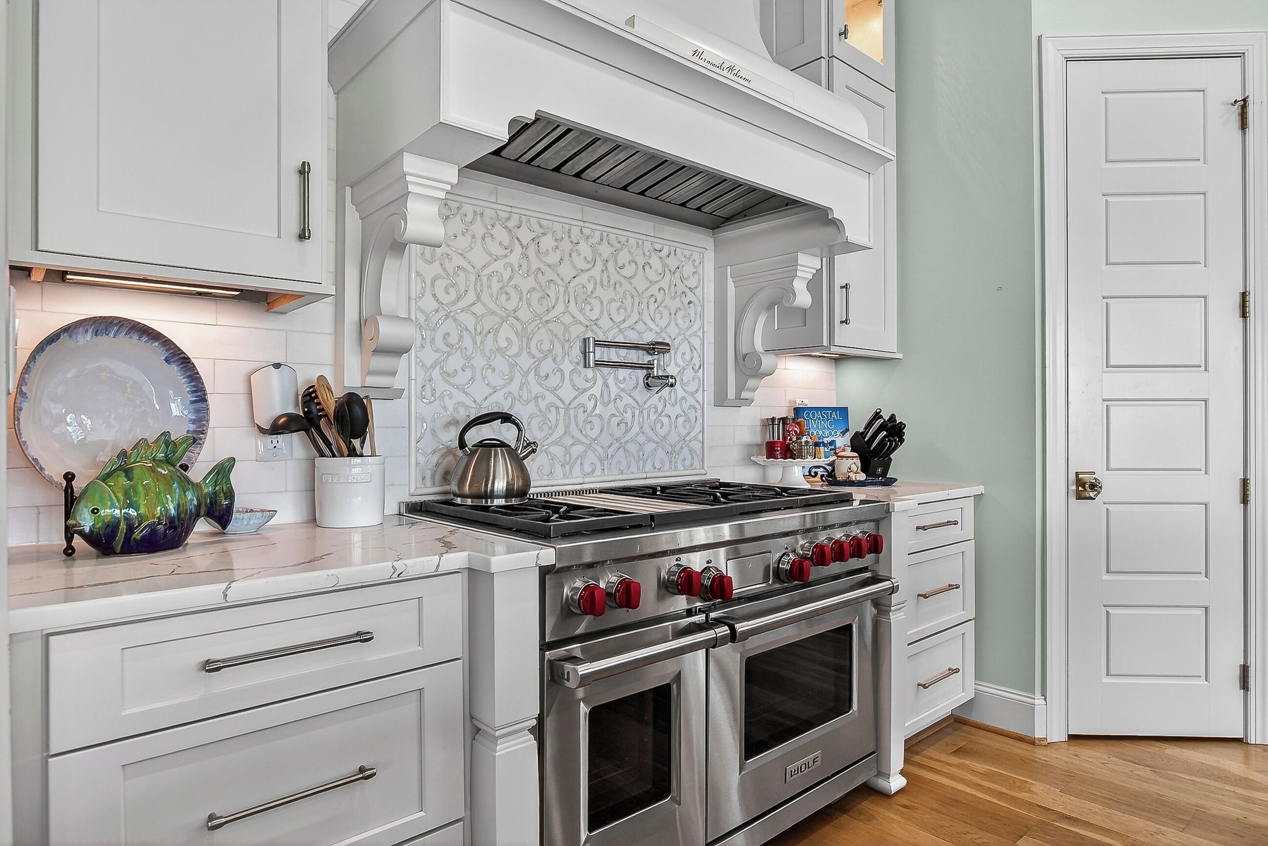 A kitchen with white cabinetry, a stainless steel stove, and a double oven.