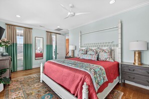 Ein Schlafzimmer mit Bett, Nachttischen, Deckenventilator und Blick ins Freie.