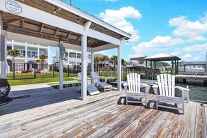 A wooden deck with lounge chairs and a covered area overlooking a marina. - Canalfront dock, game room and elevator (Surf City)