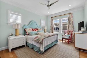 A bedroom with a bed, nightstands, a chair, a television, and a ceiling fan. - Canalfront dock, game room and elevator (Surf City)