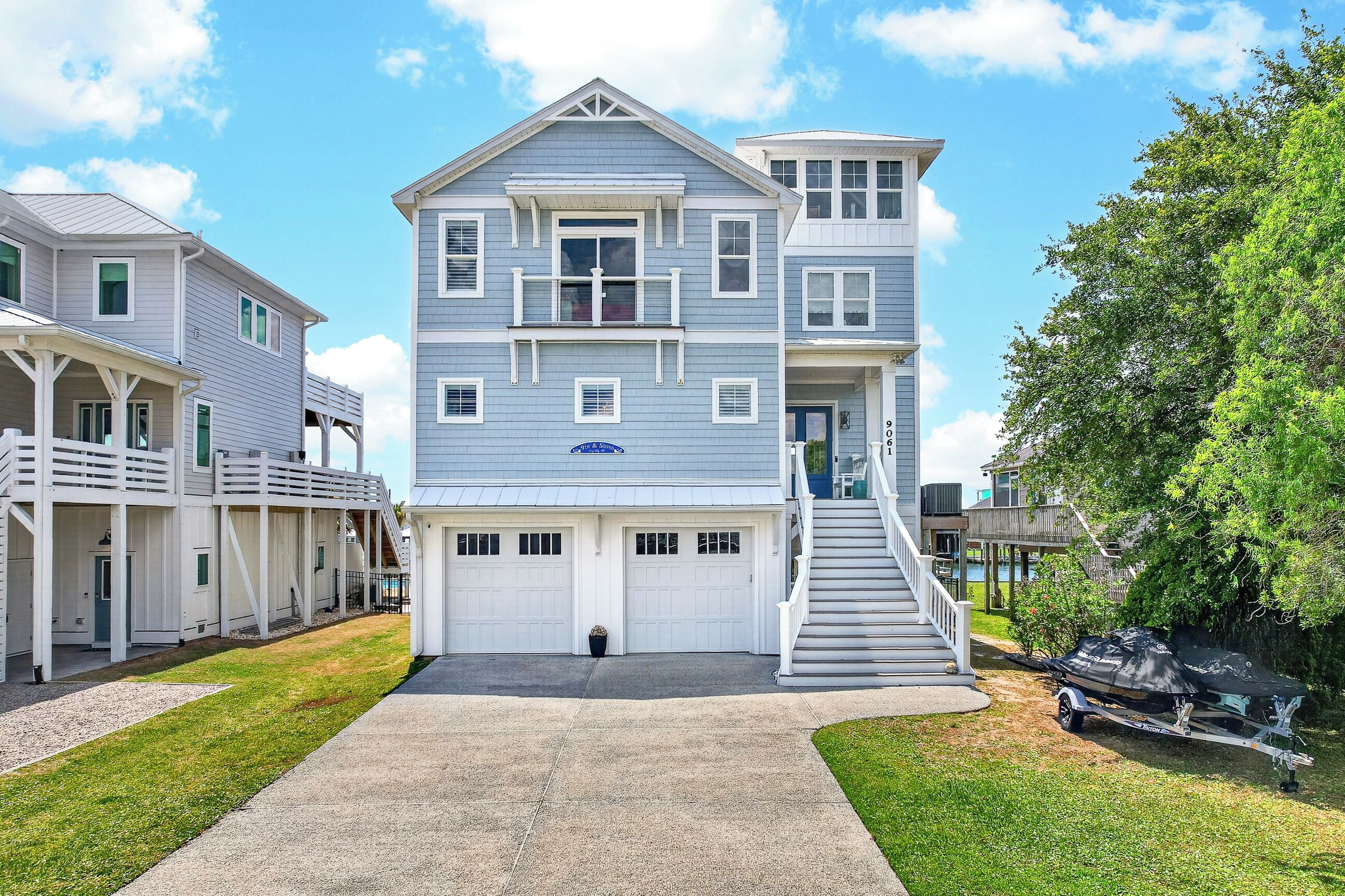 A multi-story residential building with a garage, a covered porch, and a staircase leading to the upper floors.
