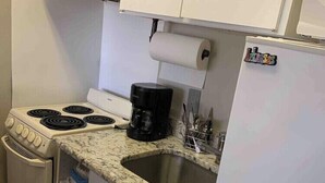 Une petite cuisine équipée d’une cuisinière, d’une machine à café, d’un évier et d’un réfrigérateur.