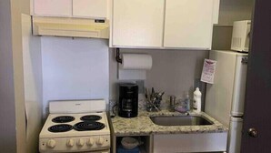 Une cuisine de taille réduite, avec un fourneau blanc, un évier et des placards.