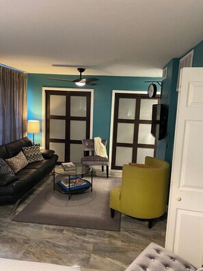 A living room with a sofa, armchair, coffee table, and a television. - 2720 #104 Oaklawn furnished rental (Dallas)
