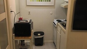 A compact kitchen with a stove, a microwave, and a small trash bin. - Stay in Style! Heart of Dallas 106 (Dallas)