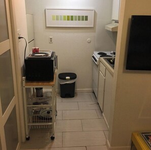 A compact kitchen with a stove, a microwave, and a small trash bin. - Stay in Style! Heart of Dallas 106 (Dallas)