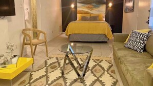 A bedroom with a bed, a sofa, a glass coffee table, and a chair. - Stay in Style! Heart of Dallas 106 (Dallas)